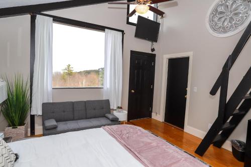 a bedroom with a bed and a couch and a window at Gunstock Inn & Suites in Gilford