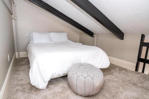 a bedroom with a large white bed and a stool at Gunstock Inn & Suites in Gilford