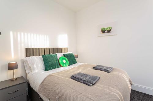 ein Schlafzimmer mit einem Bett mit zwei grünen Kissen in der Unterkunft Cherry Property - Kiwi Suite in Blackpool