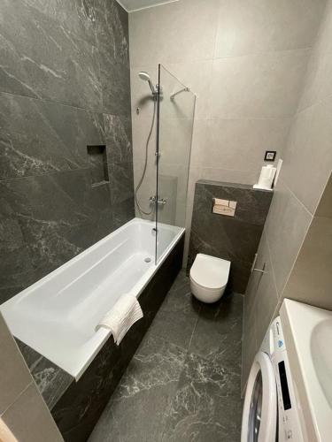 a bathroom with a tub and a toilet and a sink at Arcadia apartment & sea terrace in Odesa