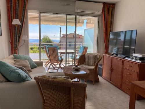 un soggiorno con divano, TV e balcone di Résidence avec piscine, plage à 100 m, Cannes et Juan les Pins à 5 min, WiFi a Golfe-Juan