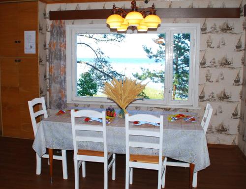 a dining room with a table and chairs and a window at Karineeme Holiday House in Mahu