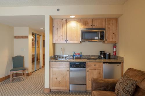 a small kitchen with wooden cabinets and a couch at Grand Lodge Condo in the Heart of Mt Crested Butte condo in Crested Butte