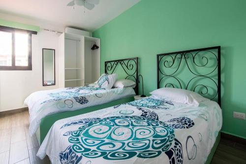 duas camas num quarto com paredes verdes em Casa Korima Cancun - Luxurious - Budget Friendly em Cancún