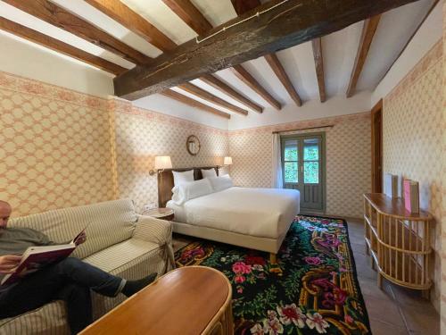 un dormitorio con una cama y una persona sentada en un sofá en Casa Palacio Armiñón en Armiñón