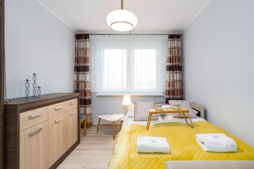 Osiedle Orła Białego Apartament Poznań في بوزنان: غرفة نوم بسرير اصفر وطاولة