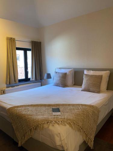 a bedroom with a large white bed with a window at Guesthouse Vakantie Logies Hollywood in Bruges