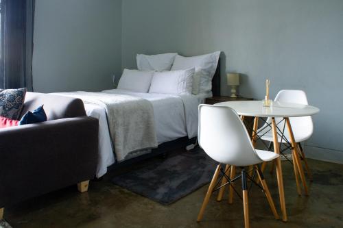 a bedroom with a bed and a table and chairs at Lux Studio Apartment @ Hallmark House in Johannesburg