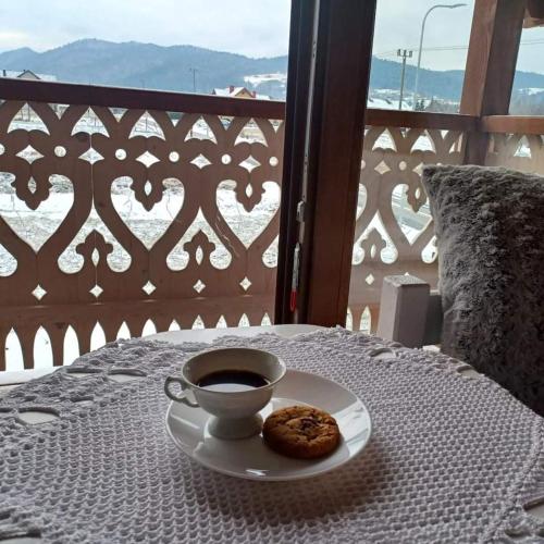 a cup of coffee and a cookie on a table at Gazdówka - najlepsza miejscówka domek w Pieninach in Krościenko
