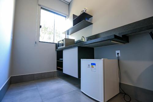 a kitchen with a white refrigerator and a window at Vila Castelo Residencial no Centro de Foz in Foz do Iguaçu