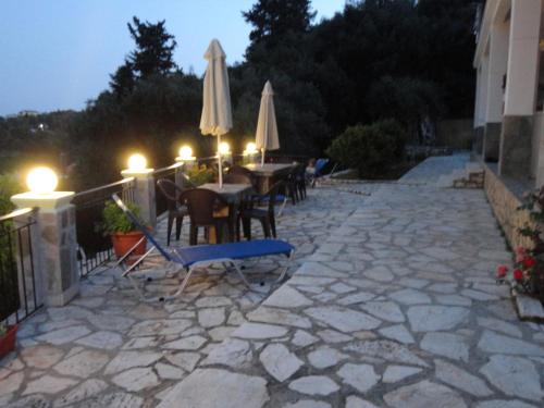 a patio with a table and chairs and umbrellas at Stamatela Studios in Paleokastritsa