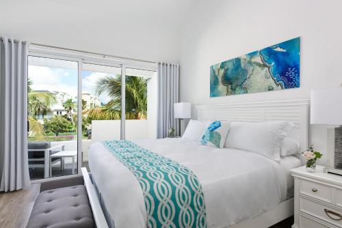 a white bedroom with a bed and a large window at Zenza Boutique Hotel in Providenciales