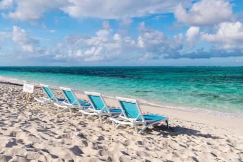 a row of lounge chairs on a sandy beach at Zenza Boutique Hotel in Providenciales