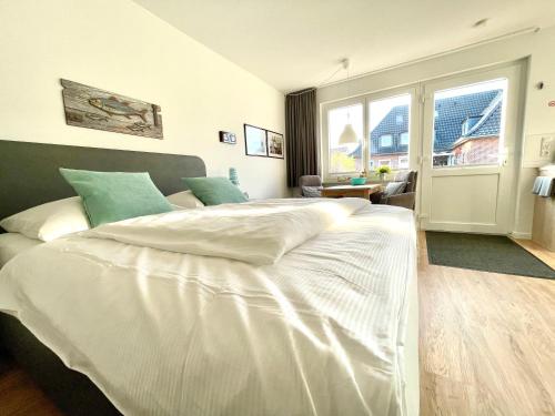 sypialnia z dużym białym łóżkiem i oknem w obiekcie Fischerbude w Büsum