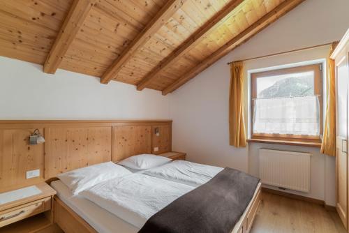 Schlafzimmer mit einem Bett und einem Fenster in der Unterkunft Apartments Ansciuda in St. Ulrich in Gröden