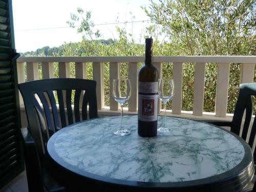 a bottle of wine sitting on a table with two wine glasses at Apartments Suzana in Ždrelac