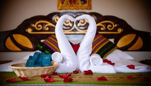 Una cama con dos toallas de cisne y una cesta de regalos. en Hotel Boutique Gold Garden, en Cusco