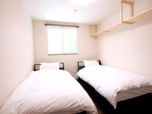 two beds in a small room with a window at Koropokuru - Vacation STAY 91481v in Niseko