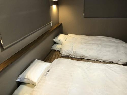 Duas camas num quarto com lençóis e almofadas brancos em Kikuya Cottage - Vacation STAY 92195v em Yamanakako