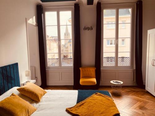a bedroom with a bed and two large windows at L'expérience d'Elie by Icone Collection in Caen