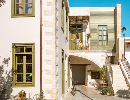 a woman standing on the balcony of a building at Neratze Hammam Suites in Rethymno Town