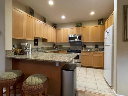 Una cocina con gabinetes de madera y un refrigerador blanco. en Nihilani 11A condo, en Princeville