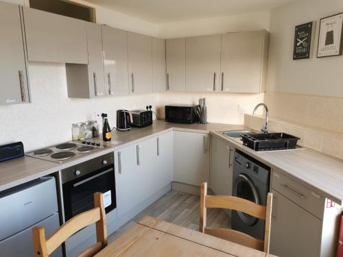 a kitchen with white cabinets and a sink and a dishwasher at The Captains Quarters in Scarborough