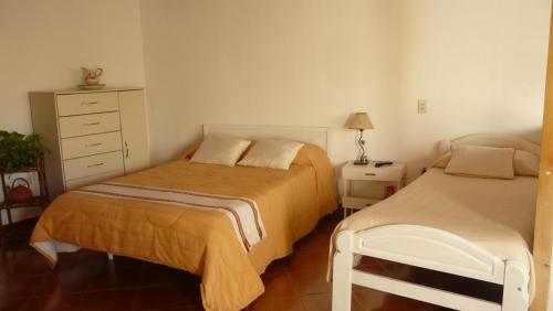 een slaapkamer met 2 bedden en een dressoir bij El Jardin de Nora in Tandil