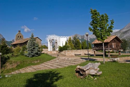 a park with a white building and a tree at Hotel Presa in Riaño