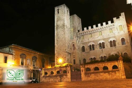 a large building with a clock tower at night at Hotel Pennile in Ascoli Piceno