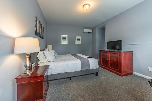 a bedroom with a bed and a desk and a television at Homestead Inn in New Milford