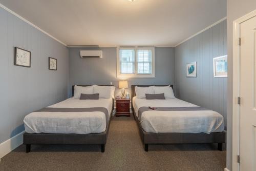 two beds in a room with blue walls at Homestead Inn in New Milford