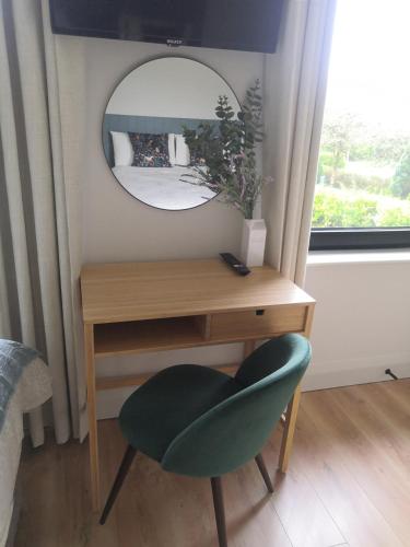 a desk with a green chair and a mirror at Cedar Lodge in Killarney