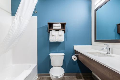 a blue bathroom with a toilet and a sink at WoodSpring Suites Elgin - Chicago in Elgin