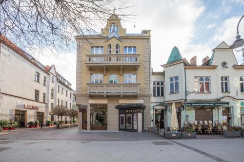 a tall yellow building with a balcony on a street at Sopot Pier Apartments by OneApartments in Sopot