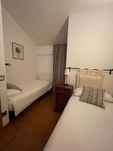 a bedroom with two beds and a night stand with a lamp at Apartaments Casa Vella Popaire in Soldeu