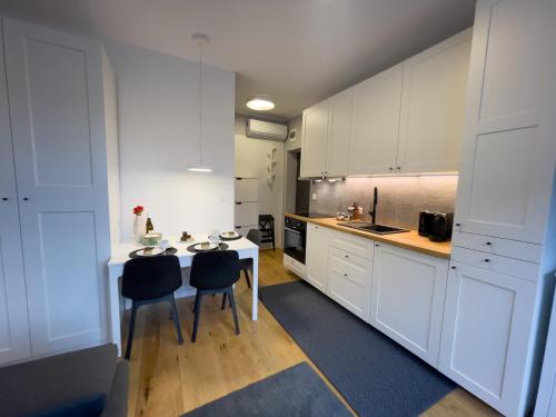 a kitchen with white cabinets and a table and chairs at URBAN APARTMENTS STUDIO No 3A Chorzów Katowice, FREE PRIVATE PARKING in Chorzów