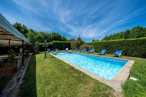 una piscina en un patio con sillas azules en Quinta do Carvalhal Casa Privada, Penafiel, en Irivo