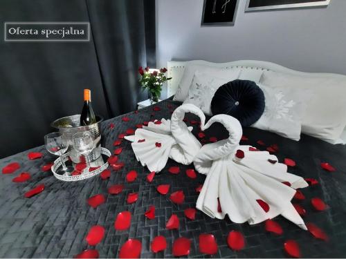 two white swans sitting on a bed with red hearts at Apartament 10 Glamour Aquapark Reda in Reda