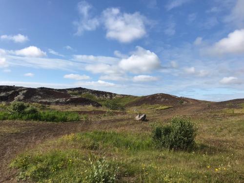a field of grass with hills in the background at Adorable Tiny House in Reykjavik in Gufunes