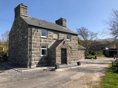 an old stone building with a black door at Bryn Y Bwyd Farm House in Barmouth