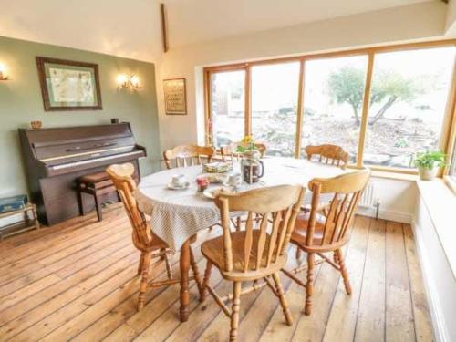 a dining room with a table and chairs and a piano at Bryn Y Bwyd Farm House in Barmouth