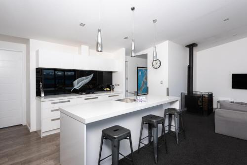 a kitchen with a white counter and stools at Silver Fern - Lake Tekapo in Lake Tekapo