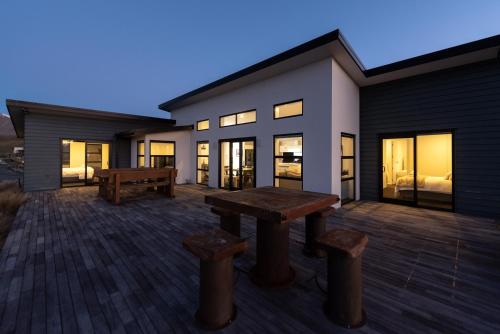 a patio with a table and benches in front of a house at Silver Fern - Lake Tekapo in Lake Tekapo