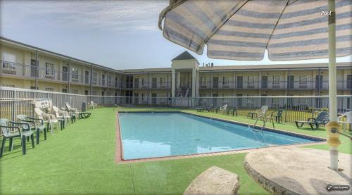 a hotel with a swimming pool with chairs and an umbrella at Econo Lodge in Corbin