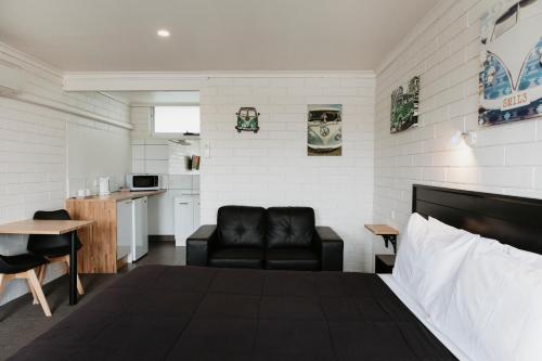 a bedroom with a bed and a couch and a kitchen at Anchor Wheel Motel in St Helens