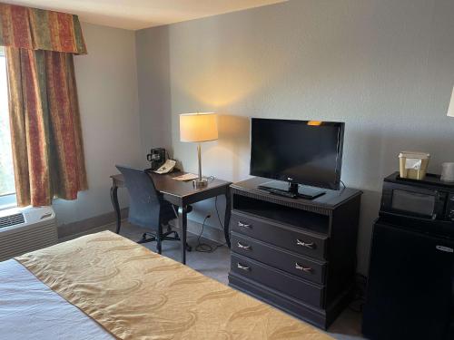 a hotel room with a bed and a desk with a television at SureStay Plus Hotel by Best Western Durham Medical Center in Durham