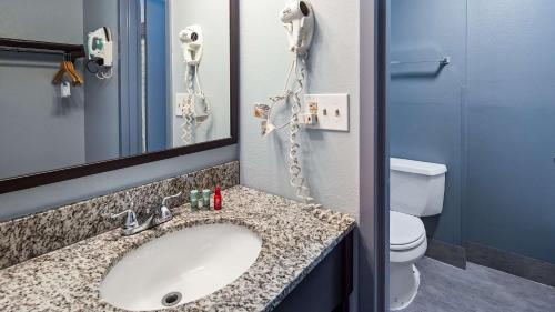 a bathroom with a sink and a phone next to a toilet at SureStay Plus Hotel by Best Western Durham Medical Center in Durham