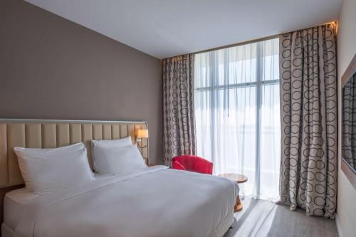 a bedroom with a large bed and a large window at Radisson Resort Ras Al Khaimah Marjan Island in Ras al Khaimah