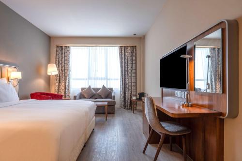 a hotel room with a bed and a desk and a television at Radisson Resort Ras Al Khaimah Marjan Island in Ras al Khaimah